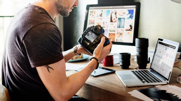 Man holding camera in front of laptop